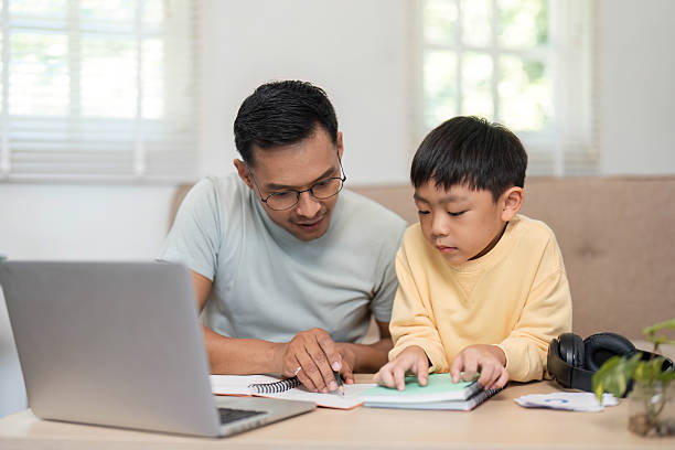 istock Homeschool father assisting son with studies at home 2215000429