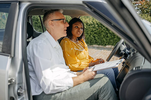 istock Young woman taking driving lessons with her instructor who is explaining different functions in car 2215000825