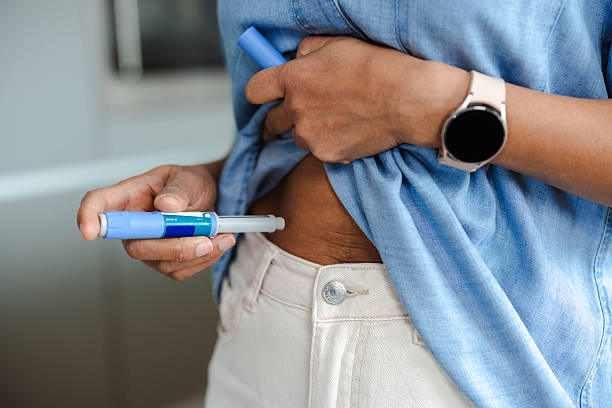 istock Person administering medication using a pen injector at home 2215002061