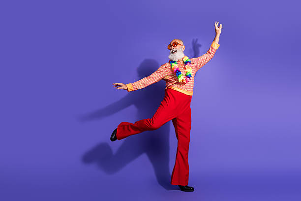 istock Charismatic elderly man in retro style disco outfit dancing energetically against a purple studio background 2215002564