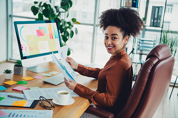 istock Confident young businesswoman in a modern office setting holding charts and presenting business data 2215003211