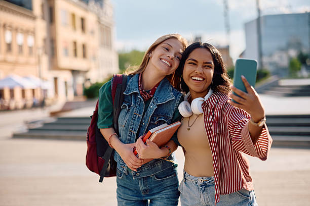 istock Carefree female students having fun while taking selfie outdoors. 2215003860