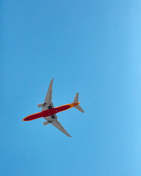istock A red and yellow airplane flies in a clear blue sky. 2215004107