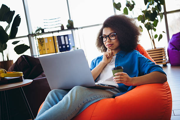 istock Young professional woman working remotely in a comfortable and trendy office setup with a laptop and coffee 2215004648