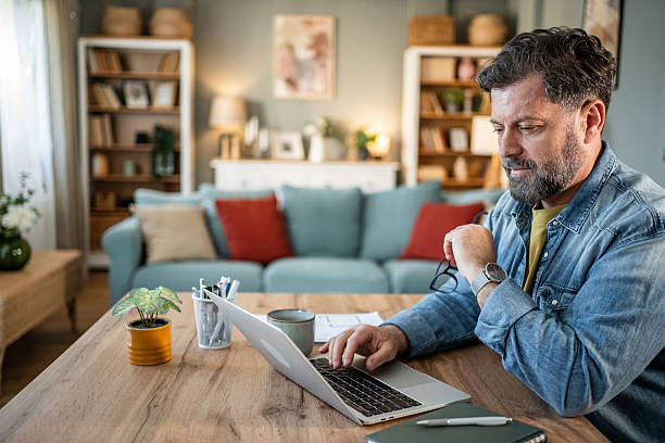 istock Focused mature freelancer working on laptop at home office 2215004826