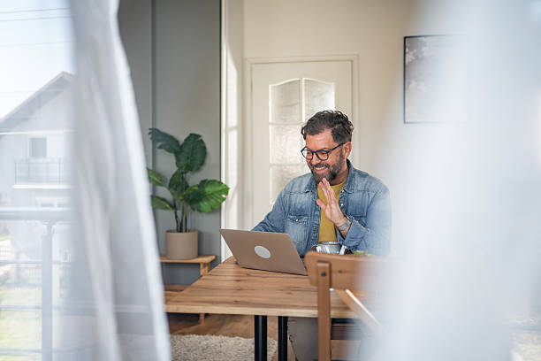 istock Happy mature freelancer waving during video call at home office 2215004897