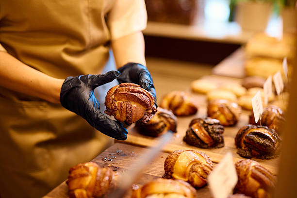 istock Baker wearing black gloves presenting a freshly baked cinnamon roll in a bakery 2215007973