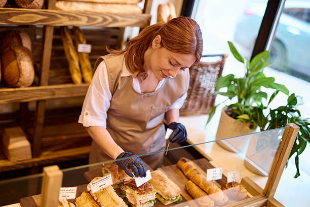 istock Baker arranging sandwiches in display case of bakery 2215008191