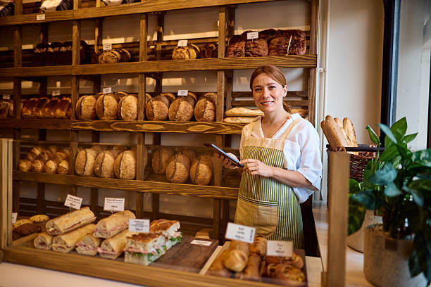 istock Smiling baker woman using digital tablet managing bakery shop 2215008440