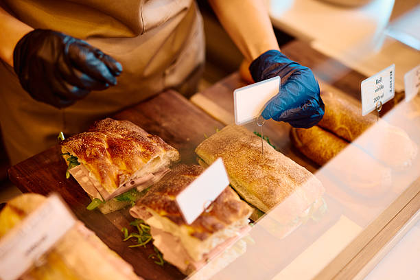 Baker arranging fresh sandwiches in display case