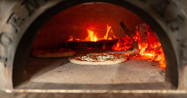 istock Delicious pizzas baking in a traditional wood-fired oven 2215009822