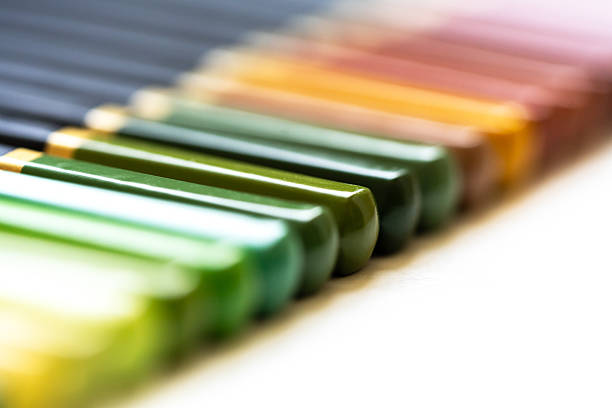 Organized set of colored pencils in a white surface, sorted by hue from warm to cool tones. Vibrant and creative art supplies, soft focus on pencil tips and colors. Selective focus