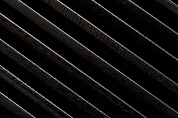 Close-up of black wooden pencils arranged in diagonal lines, forming a modern striped pattern with soft light reflections. Minimalist artistic texture and creative vibe.