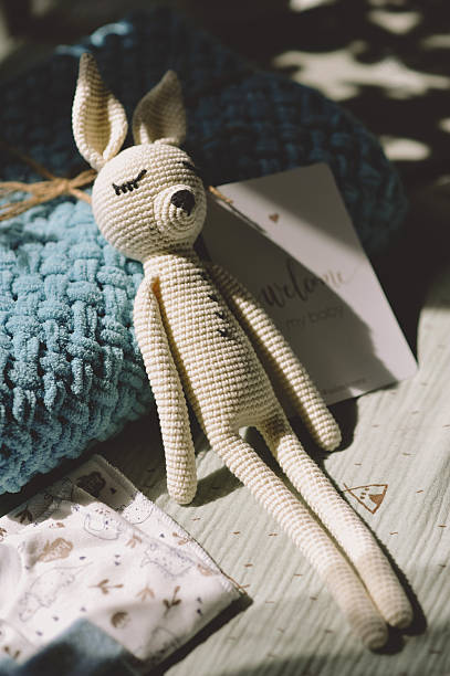 Knitted white bunny in the comfortable crib. Knitted rabbit. Expecting a baby