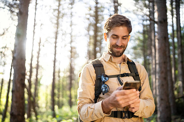istock Man hiking in a forest using smartphone during a sunny day journey 2215012376