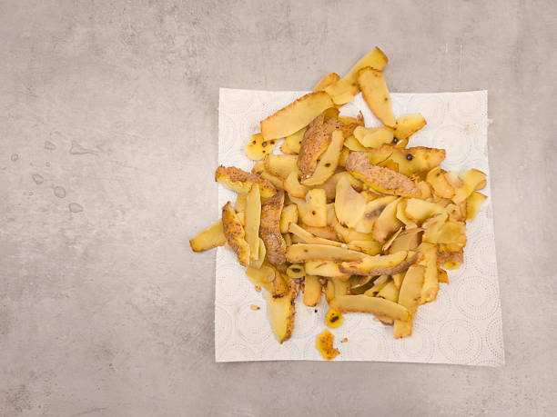 Potato peels are drying on an absorbent paper towel after being peeled, showcasing food waste or potential use in cooking, copy space