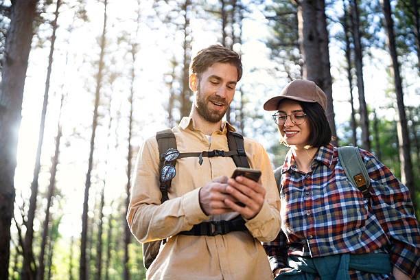 istock A cheerful couple hiking in a scenic forest, exploring nature while checking navigation on a smartphone 2215012853