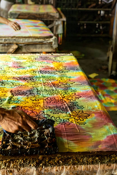 istock Artisan applying batik stamp on colorful fabric in workshop 2215013136