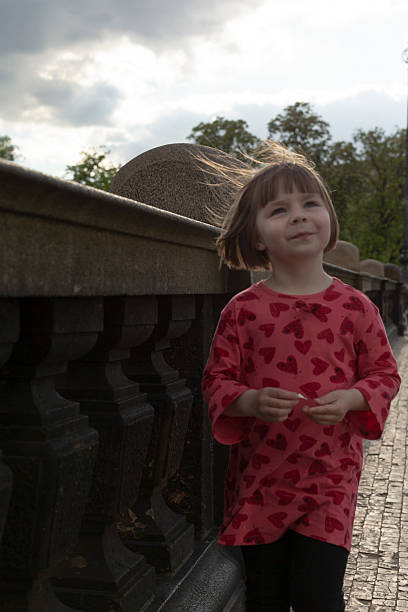 A cheerful girl in a heartpatterned dress is happily walking along a scenic path in a lovely park on a sunny day