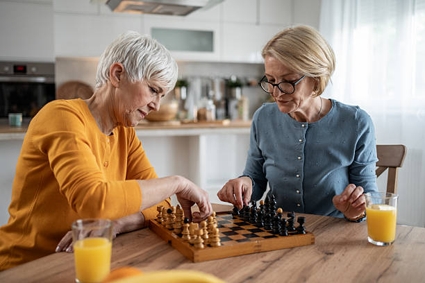 istock Two senior women playing chess at home while drinking orange juice 2215015854