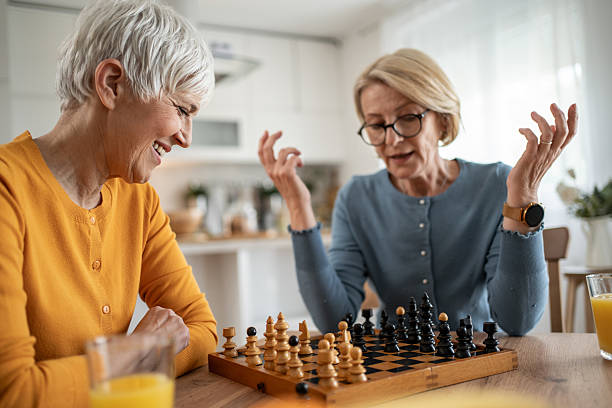 istock Two senior women playing chess and having fun at home 2215015873
