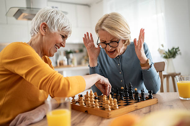 istock Two senior women playing chess and having fun at home 2215015874