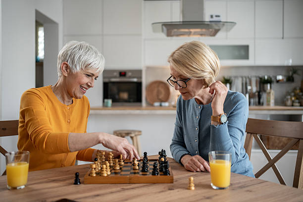 istock Two senior women playing chess and having fun at home 2215015891