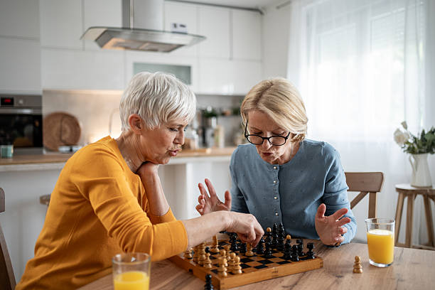 istock Two senior women playing chess and having fun at home 2215015904