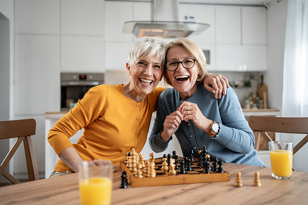 istock Two senior women playing chess and having fun at home 2215015984