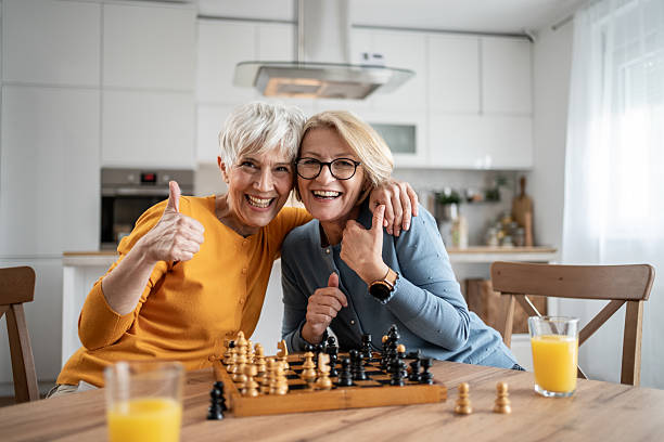 istock Two senior women playing chess and having fun at home 2215015986