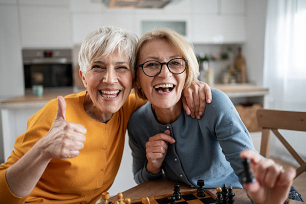 istock Two senior women playing chess and having fun at home 2215015989