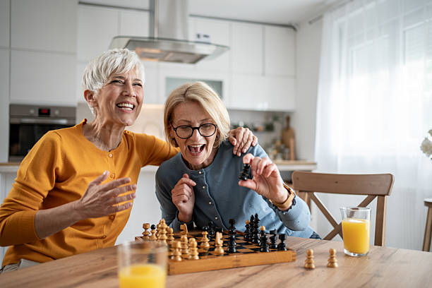 istock Two senior women playing chess and having fun at home 2215015991