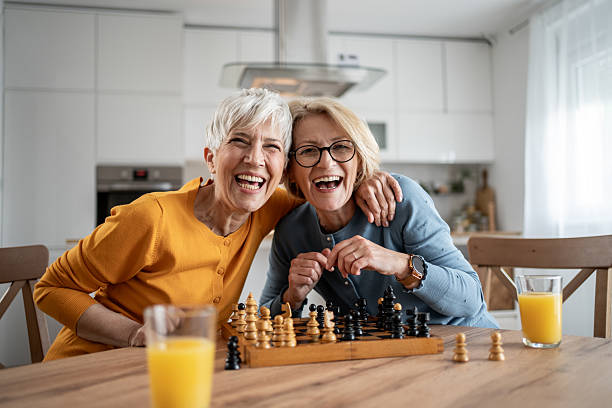 istock Two senior women playing chess and having fun at home 2215015992