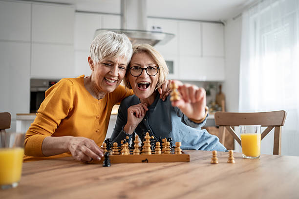 istock Two senior women playing chess and having fun at home 2215015993