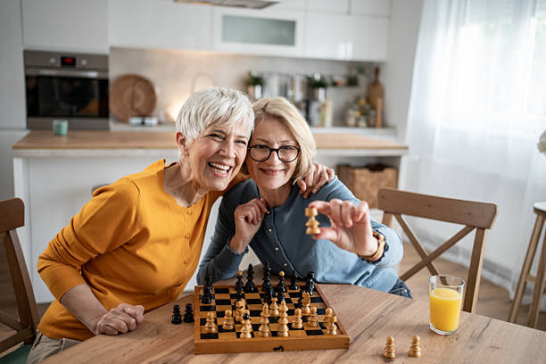 istock Two senior women playing chess and having fun at home 2215015994