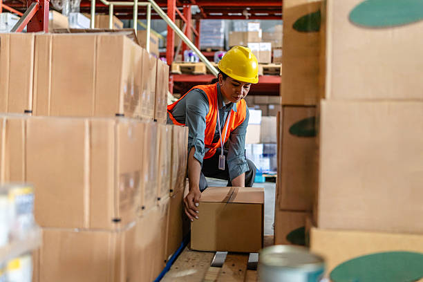 istock Warehouse worker carefully lifting a box in a busy distribution center during daytime operations 2215017095