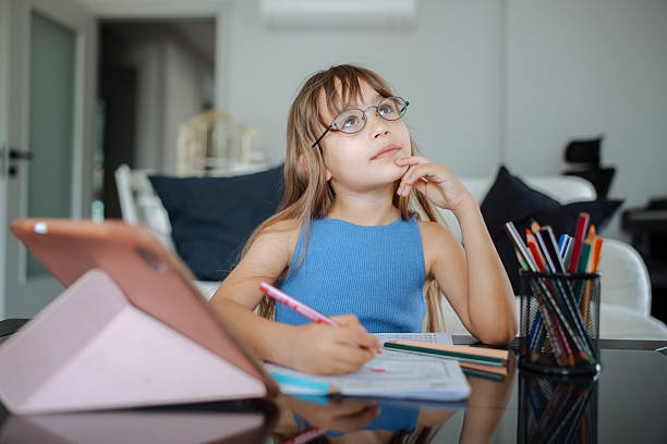 istock Portrait Of Gir Sitting At Living Room Doing Homework Using Digital Tablet 2215017963