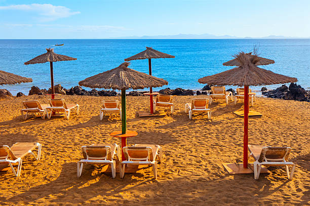 istock Serene golden sand beach with white lounge chairs 2215017969
