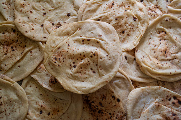 Top view of Egyptian bread (Aish Baladi) or flat bread , with background full of bread ,stacked together. A staple food in Egyptian cuisine, often served with traditional meals.