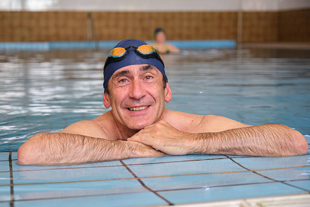 istock Mature man smiling and relaxing at the pool edge 2215019230