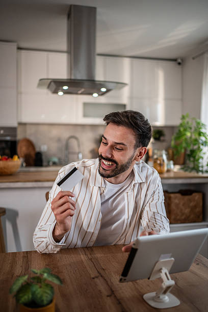 istock Young man making online payment using digital tablet and credit card at home 2215021174