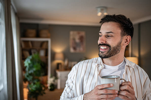 istock Young man smiling and holding a mug in his apartment 2215023688