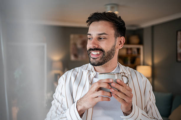 istock Young man smiling and holding a mug in his apartment 2215023715