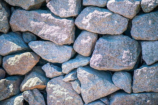 The stones allude to the patient construction of life and the symbolic structures of existence, serving as a metaphor for the resistance and beauty contained in natural imperfection.