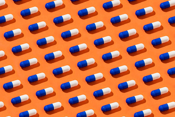 istock White Pills on Orange Colored Background 2215027993