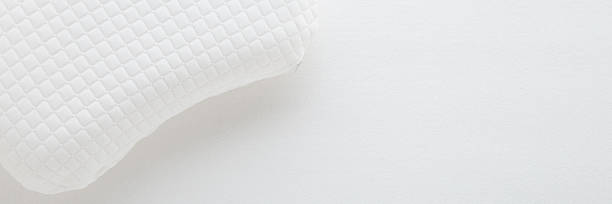 istock White soft memory foam pillow on mattress cloth background. Closeup. Wide banner. Empty place for text. Top down view. 2215028641