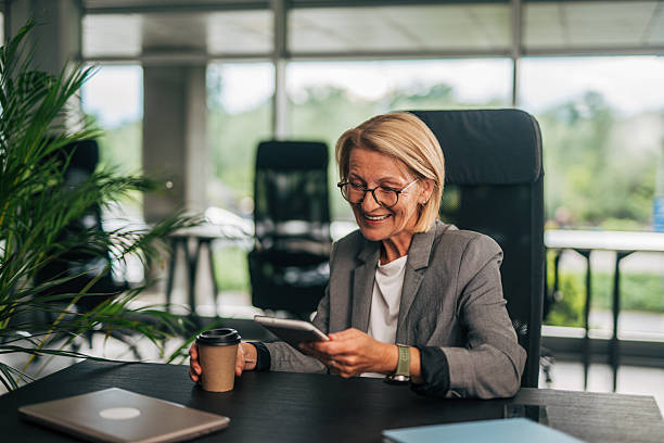 istock Senior businesswoman enjoying coffee and using digital tablet in office 2215029248