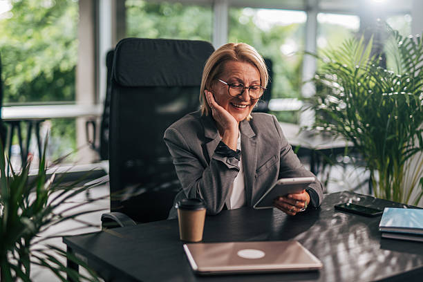 istock Senior businesswoman smiling and using digital tablet in modern office 2215029251