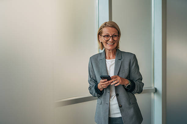 istock Smiling senior businesswoman using smartphone in modern office 2215029482