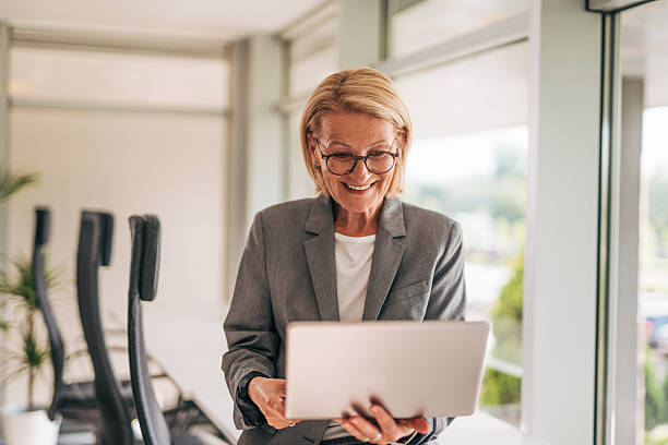 istock Senior businesswoman smiling and using laptop in office 2215029532
